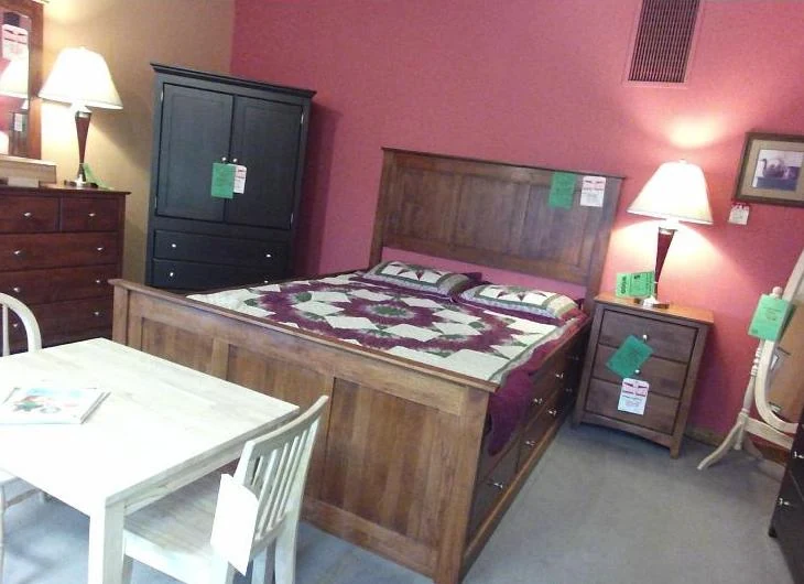 Input photo of a furniture-store bedroom with a bed, dressers, lamps and a small table with chairs